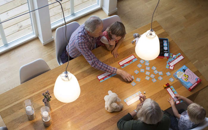 Famil spelar spel vid ett bord ses uppifrån