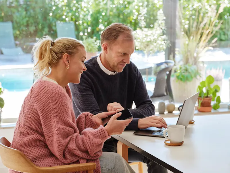 man och kvinna i ett hus sitter vid ett bord framför en dator man och kvinna i ett hus sitter vid ett bord framför en dator