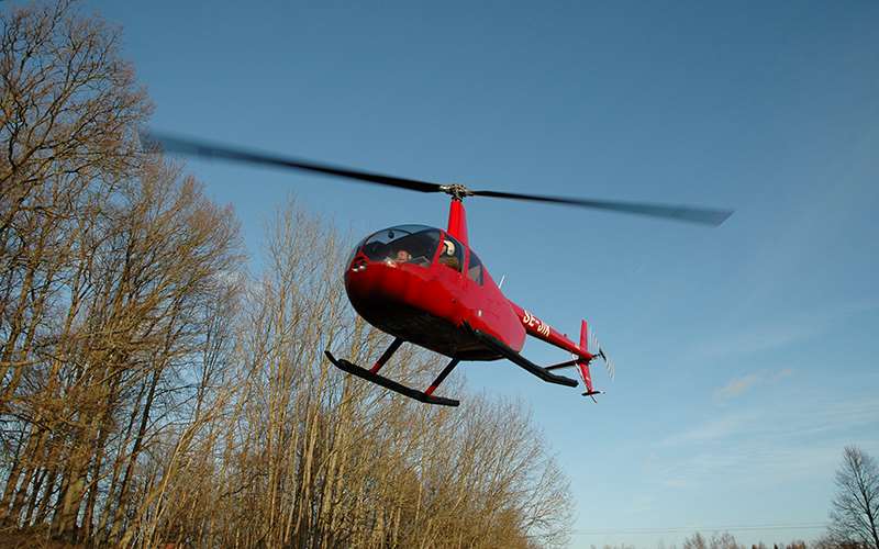 Helikopter lyfter för att inspektera elnätet.