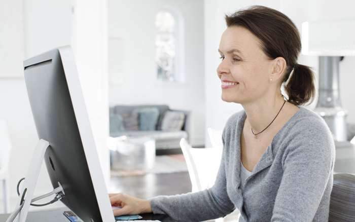 Kvinna ler och tittar i dator
