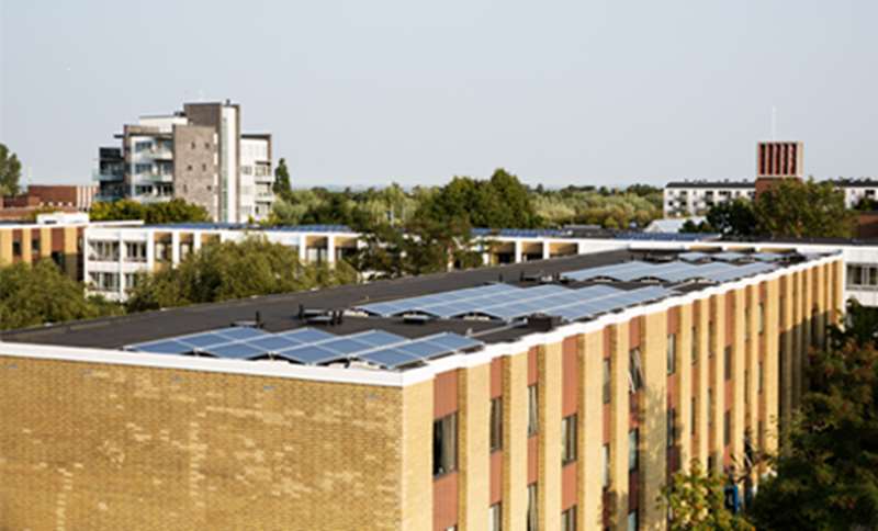 Lägenhetshus i tegel med solpaneler på det platta taket